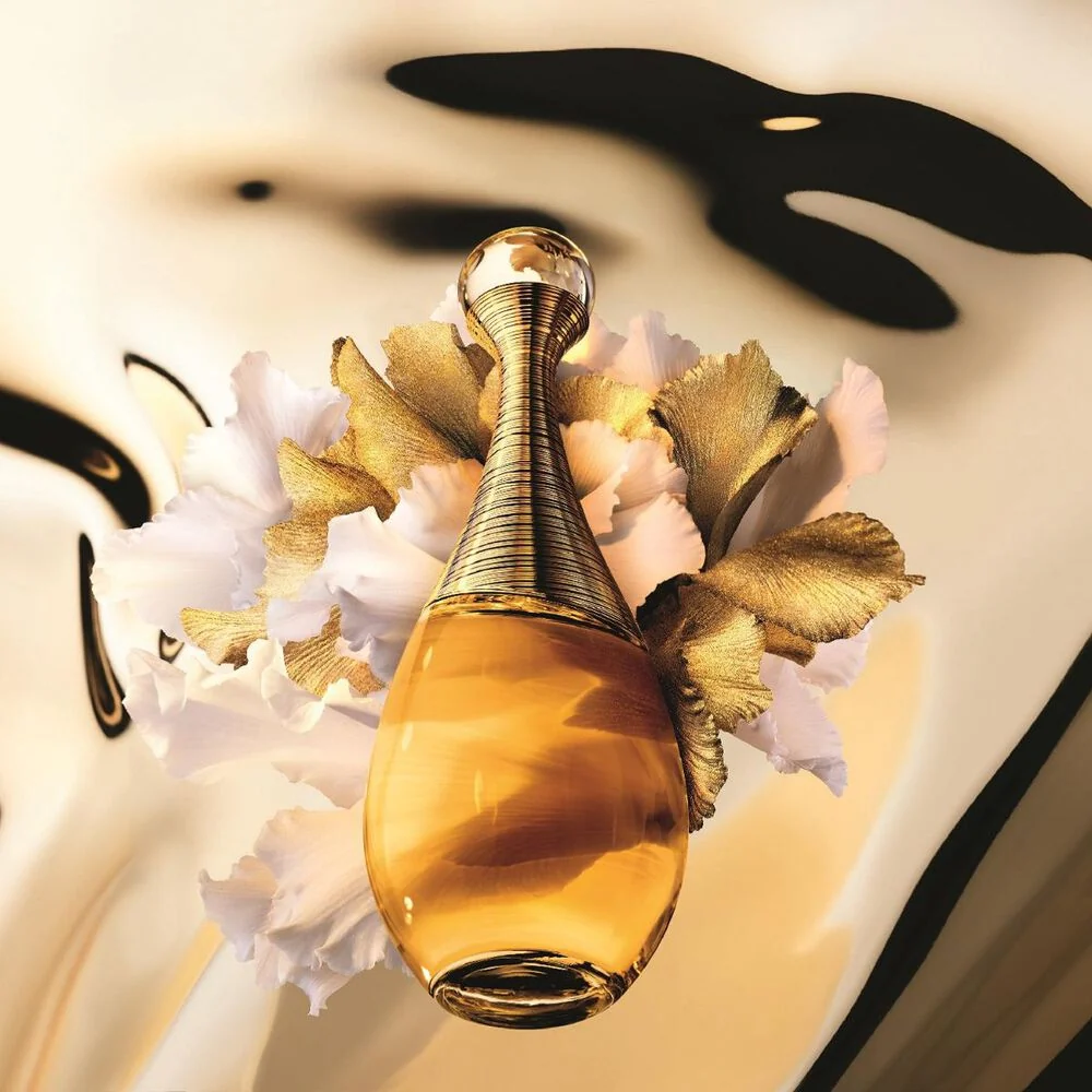 A golden J'adore bottle among white and gold flowers