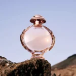 Paco Rabanne Olympea Eau De Parfum 80ml bottle on a rock under a blue sky